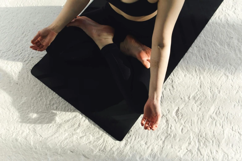 a woman is sitting on a yoga mat, by Carey Morris, trending on pexels, arabesque, panel of black, rectangle, lying down, soft rubber