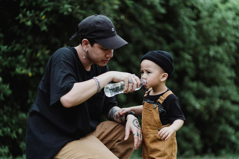 a man feeding a young boy a bottle of water, pexels contest winner, symbolism, pete davidson, goth family, avatar image, beanie