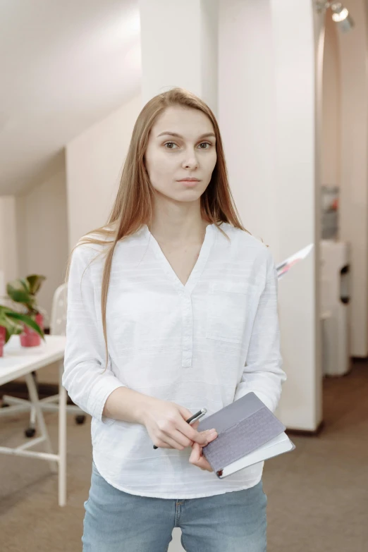 a woman standing in an office holding a clipboard, pexels contest winner, serious facial expression, ukrainian, low quality photo, an all white human