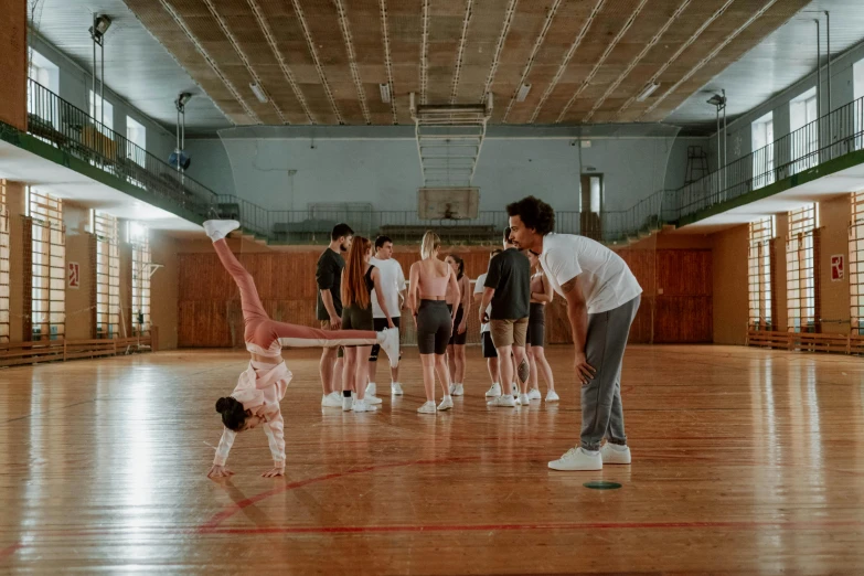 a group of people standing on top of a wooden floor, by Emma Andijewska, pexels contest winner, hyperrealism, in the high school gym, childish gambino, with a kid, acrobatic