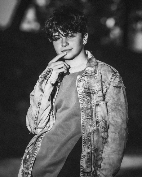 a black and white photo of a man smoking a cigarette, inspired by Kristian Kreković, jean jacket, curly and short top hair, jungkook, lgbtq