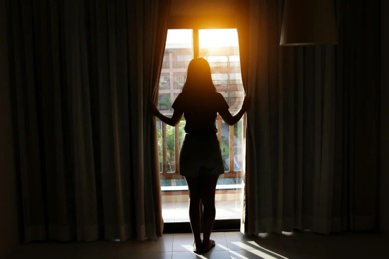a silhouette of a woman standing in front of a window, hotel room, instagram picture, sun lighting, fan favorite