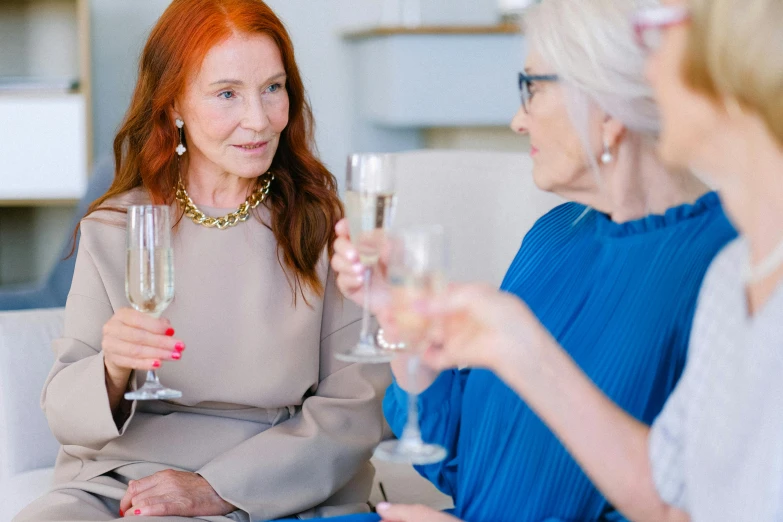 a group of women sitting on top of a couch holding wine glasses, pexels contest winner, renaissance, older woman, woman with red hair, champagne commercial, on a white table