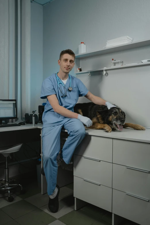 a man sitting on top of a desk next to a dog, clean medical environment, jakub rebelka, profile image, low quality photo
