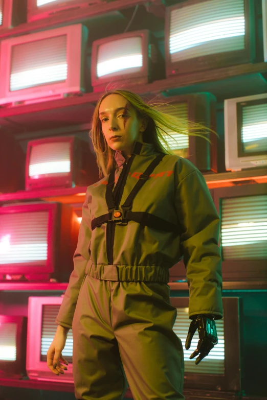 a woman standing in front of a wall of televisions, an album cover, inspired by Elsa Bleda, neo-dada, wearing human air force jumpsuit, photograph of a techwear woman, medium close-up shot, nvidia promotional image