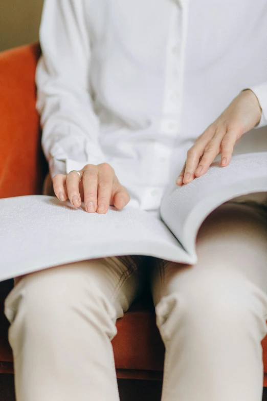 a woman sitting in a chair reading a book, wearing a white button up shirt, zoomed in, thick lining, complex features