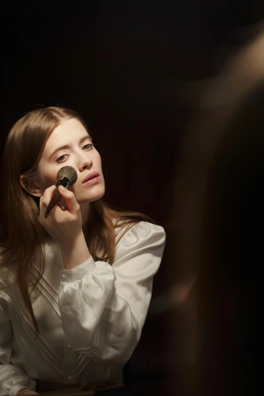 a woman sitting in front of a mirror talking on a cell phone, inspired by Wilhelm Hammershøi, renaissance, white powder makeup, ellie bamber, in front of a black background, girl with brown hair