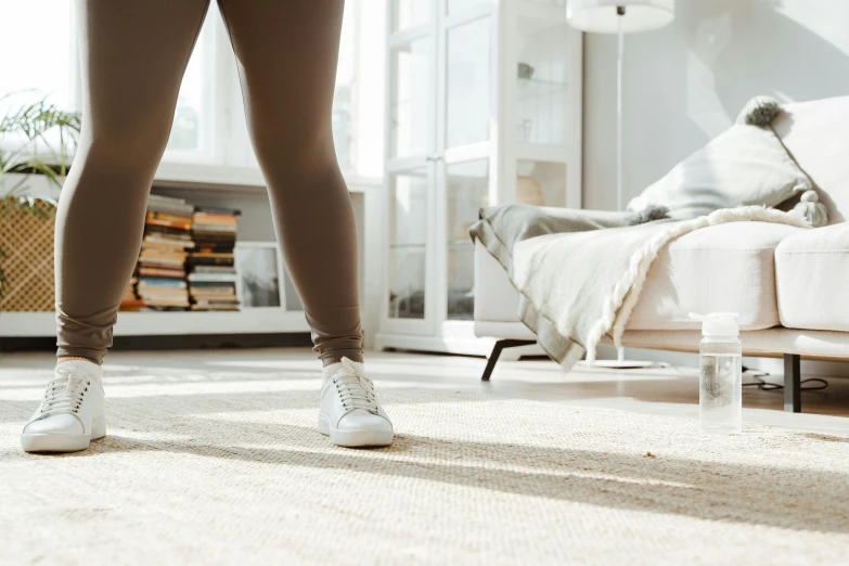 a woman standing in a living room next to a couch, trending on pexels, lunging at camera :4, fibres trial on the floor, brown and white color scheme, in my bedroom