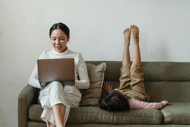 a woman sitting on a couch using a laptop, pexels contest winner, with a kid, asian descent, avatar image, people on the ground