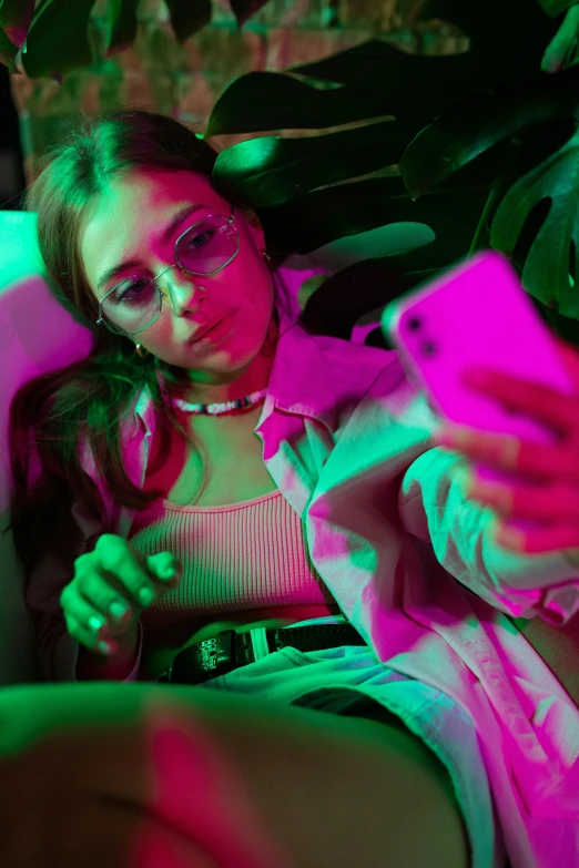 a woman sitting on a couch holding a cell phone, a picture, inspired by Elsa Bleda, trending on pexels, aestheticism, neon cyberpunk style, portrait sophie mudd, woman with rose tinted glasses, chillin at the club together