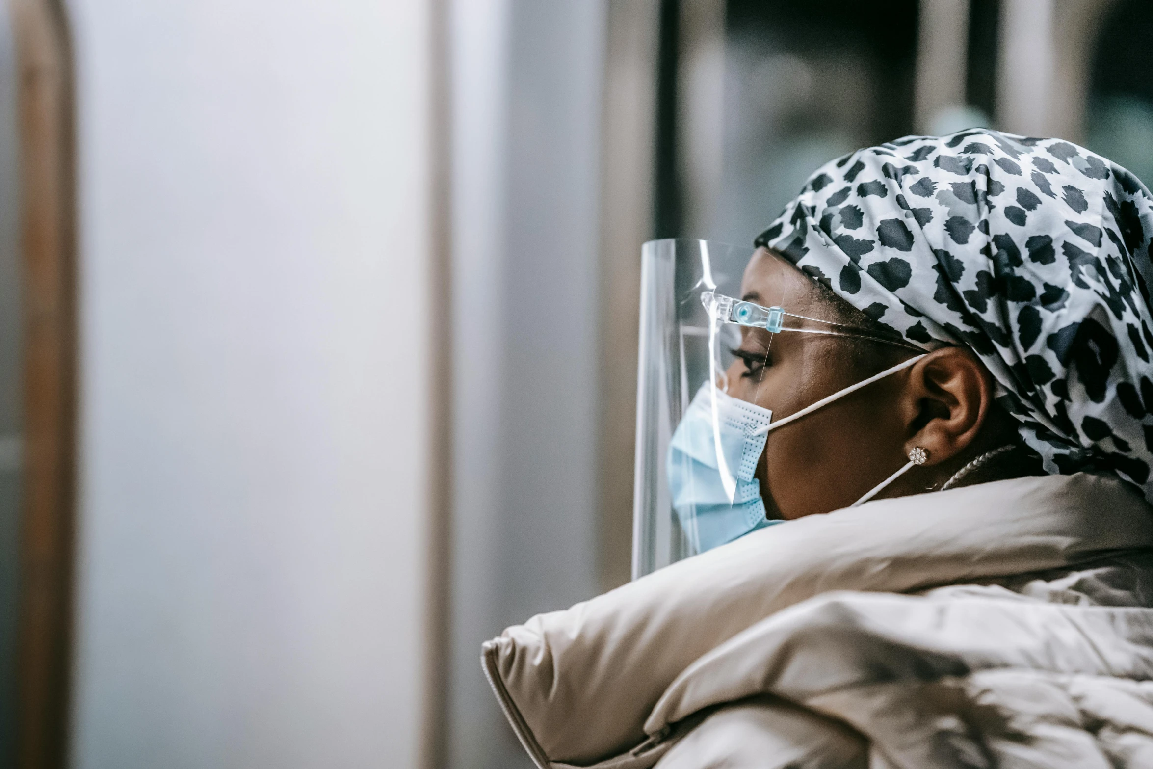 a woman wearing a face mask on a subway, trending on pexels, hurufiyya, in hospital bed, photo of a black woman, profile image, wearing lab coat and glasses