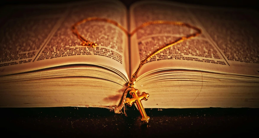 an open book sitting on top of a table, by Julia Pishtar, pexels contest winner, romanticism, gold necklace, crucifix, thumbnail, enhanced