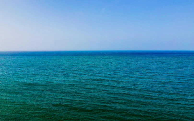 a large body of water next to a beach, inspired by Andreas Gursky, unsplash, minimalism, vibrant blue, horizon view, from wheaton illinois, colorful photograph