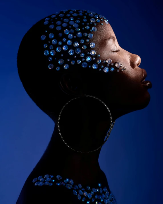 a woman with blue glitter on her face, an album cover, inspired by Bert Stern, trending on pexels, afrofuturism, embedded with gemstones, glowing with silver light, black teenage girl, albert watson