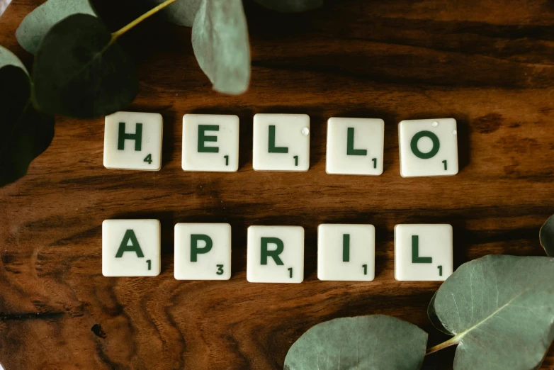 the word hello april spelled in scrabbles on a wooden table, a photo, by Arabella Rankin, trending on unsplash, happening, emerald, 1 6 x 1 6, smiling spartan, beware the ides of march