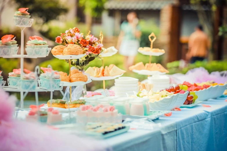 a table topped with lots of cakes and cupcakes, a tilt shift photo, unsplash, happening, picnic, pink and blue colour, featured, full-body