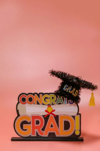 a graduation sign sitting on top of a table, by Bernie D’Andrea, pexels contest winner, solid color backdrop, hight decorated, ( 3 1, small hat