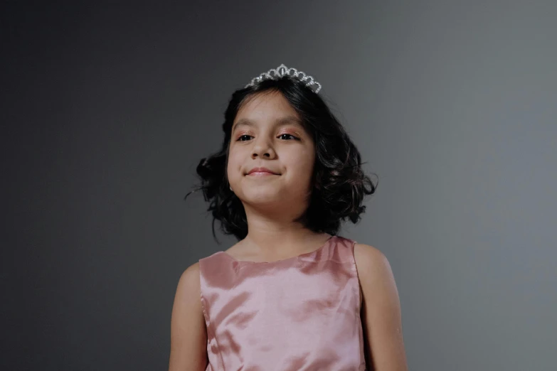 a little girl wearing a pink dress and a tiable, pexels contest winner, realism, black iron tiara, fair olive skin, ready to model, wearing silver dress