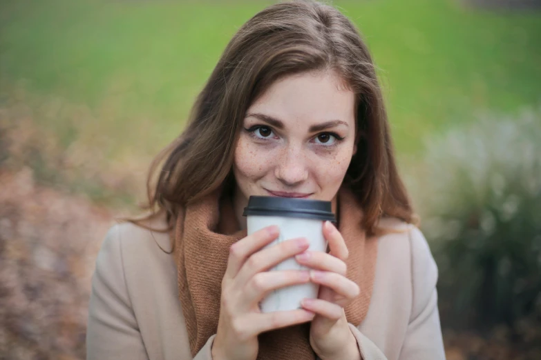 a close up of a person holding a cup of coffee, a portrait, by Julian Hatton, pexels contest winner, attractive brown hair woman, at a park, avatar image, holding a tin can