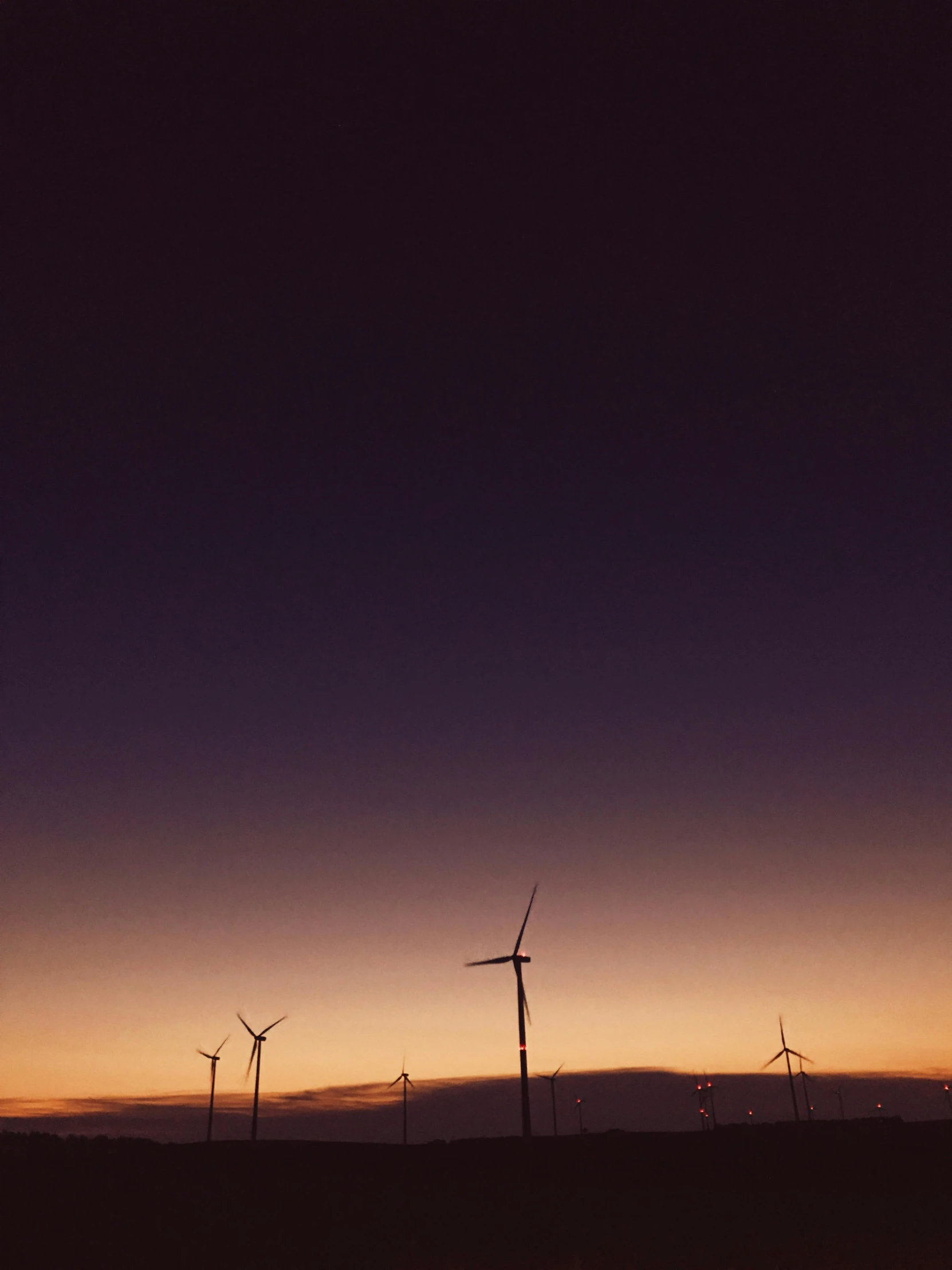 a group of windmills in a field at sunset, by Jesper Knudsen, low quality photo, dark. no text, profile image, photo on iphone