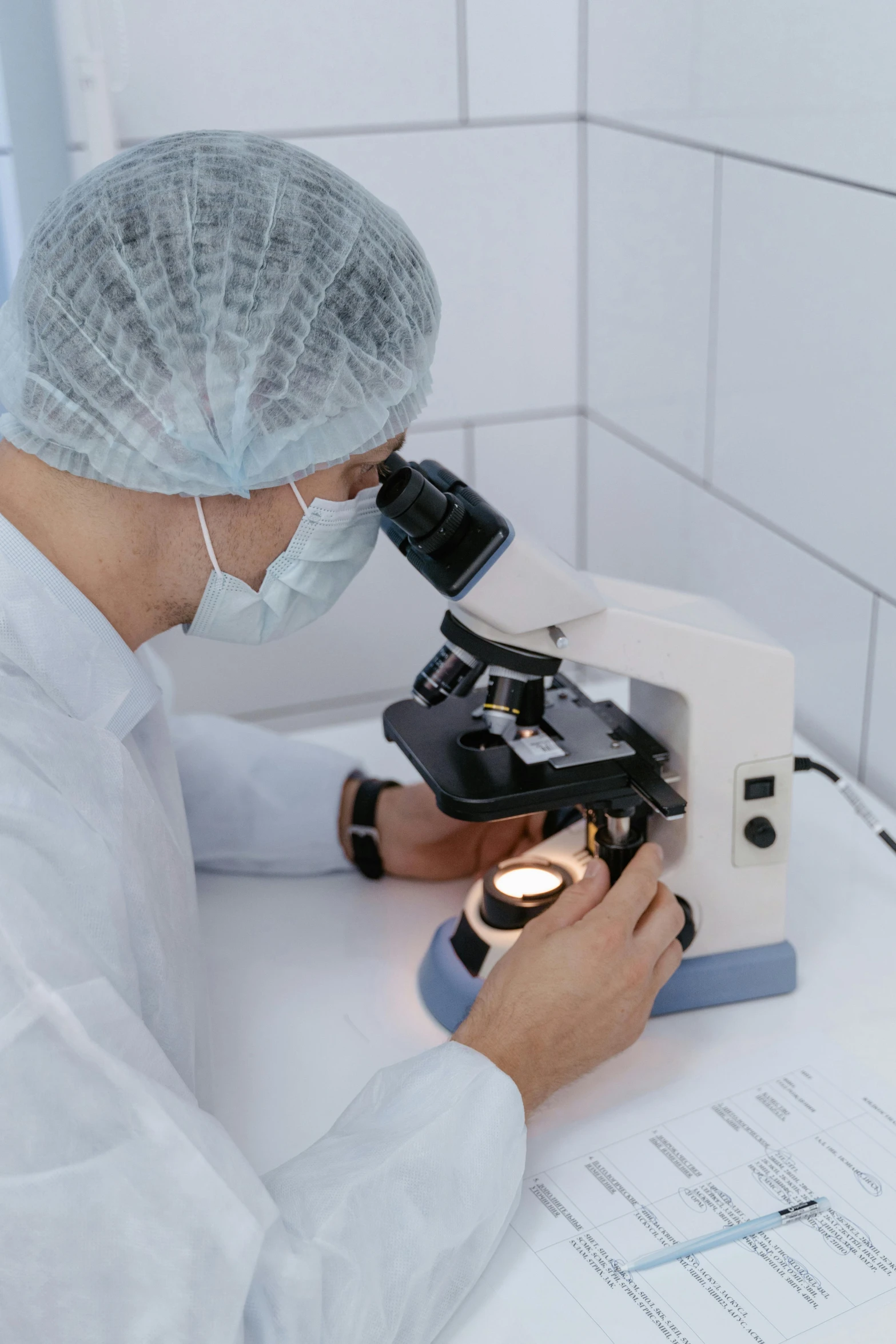 a man in a lab coat looking through a microscope, on a white table, trypophobia, thumbnail, surgical supplies