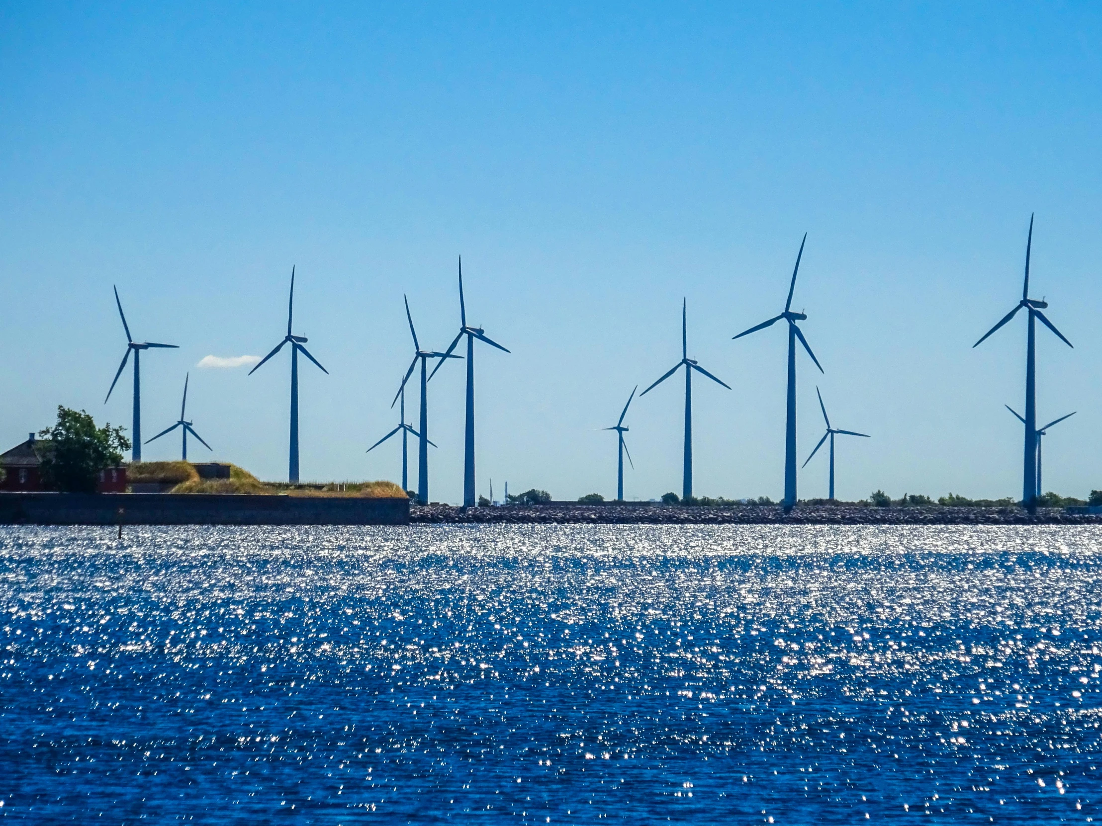 a group of wind turbines sitting on top of a body of water, by Jesper Knudsen, pexels contest winner, clear blue skies, 🦩🪐🐞👩🏻🦳, seen from a distance, thumbnail