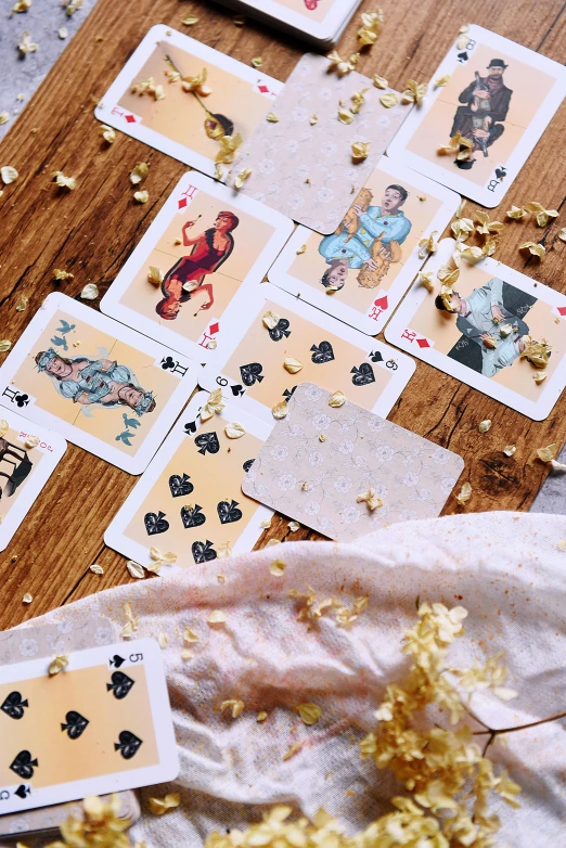 a wooden table topped with playing cards and confetti, by Julia Pishtar, unsplash, process art, gold flaked flowers, instagram story, ilustration, vintage inspired