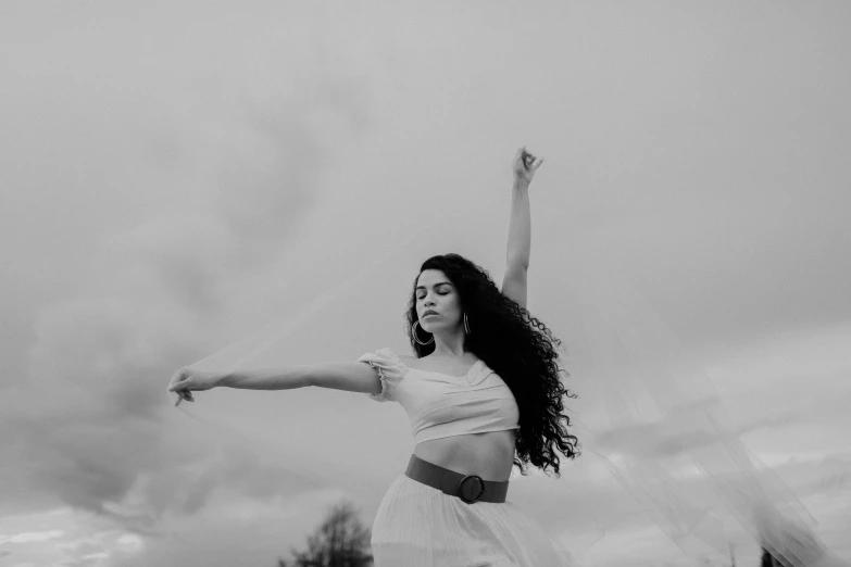 a black and white photo of a woman flying a kite, a black and white photo, by Emma Andijewska, pexels contest winner, arabesque, long windblown black hair, white curly hair, gracefully belly dancing pose, on clouds