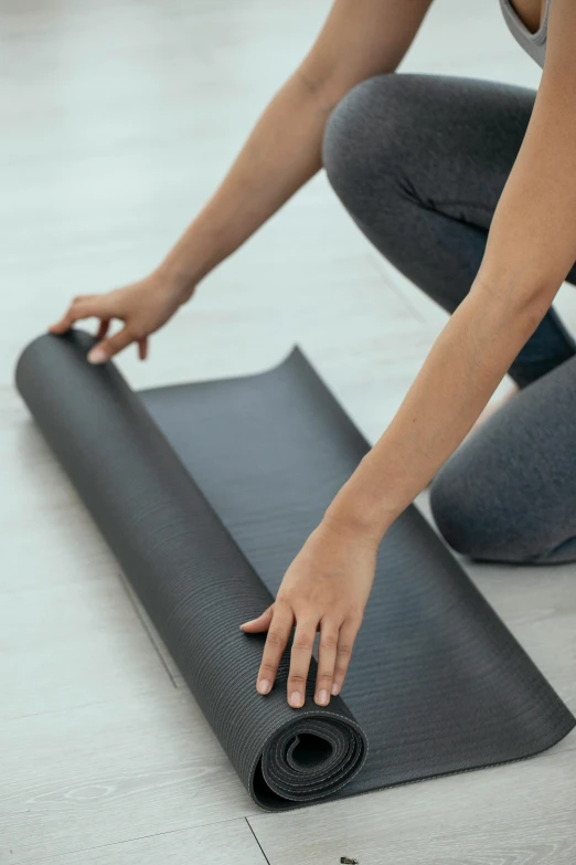 a woman rolling up a yoga mat on the floor, subtle detailing, promo image, vinyl material, graphite