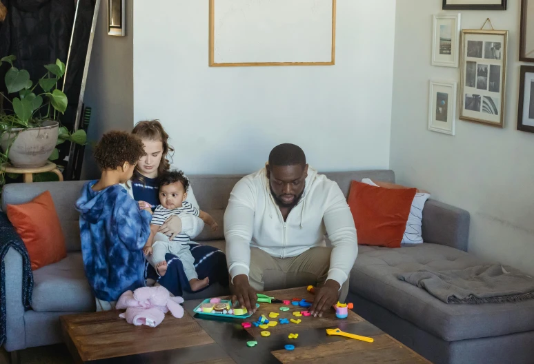 a man and two children sitting on a couch in a living room, pexels contest winner, tabletop game board, shaquille o'neil pregnant, chunky build, toddler