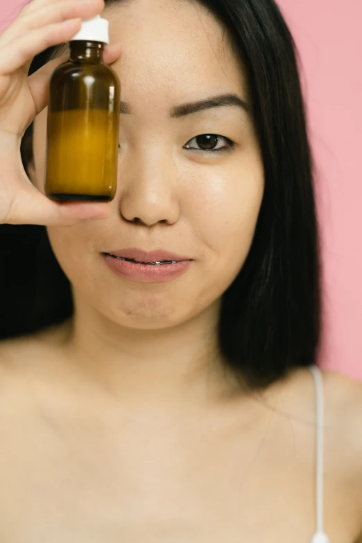 a close up of a person holding a bottle of liquid, by Julia Pishtar, asian face, wearing honey, on clear background, rectangle