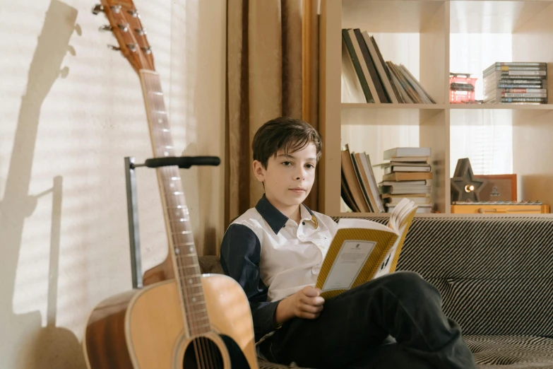 a boy sitting on a couch reading a book, an album cover, pexels contest winner, danube school, holding guitars, avatar image, medium-shot, profile picture