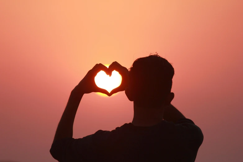 a person making a heart shape with their hands, pexels contest winner, sun behind him, profile image, loveable guy, ad image