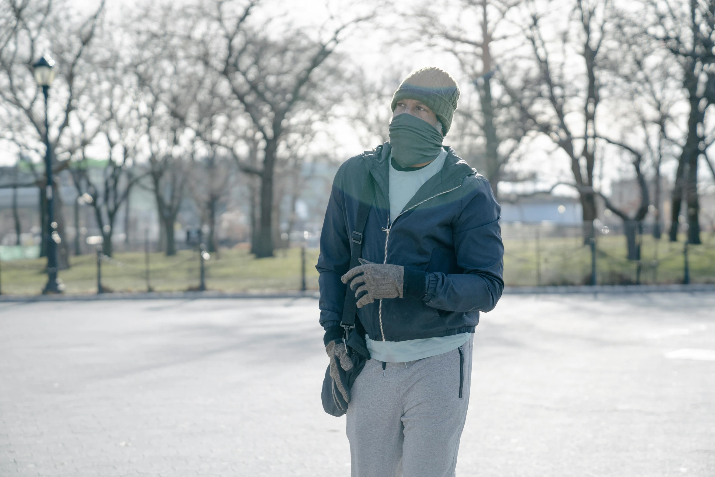 a man riding a skateboard down a street, by Andrew Stevovich, visual art, balaclava covering face, central park, gray, a green