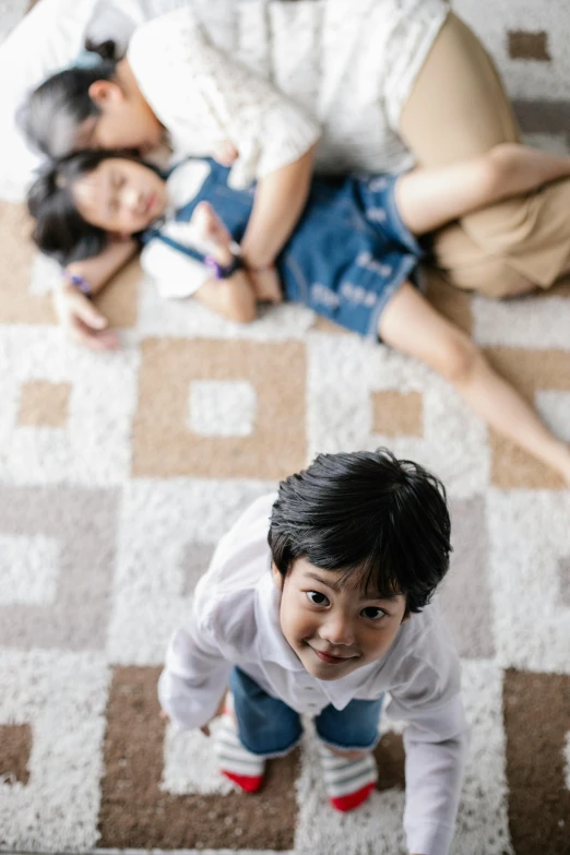 a couple of kids laying on top of a rug, by Basuki Abdullah, pexels contest winner, in a japanese apartment, above the family room, 15081959 21121991 01012000 4k, soft surfaces