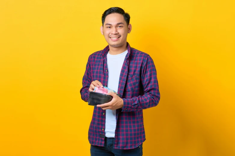 a man standing in front of a yellow wall, inspired by Rudy Siswanto, holding a leather purse, avatar image, wearing a flannel shirt, giving gifts to people