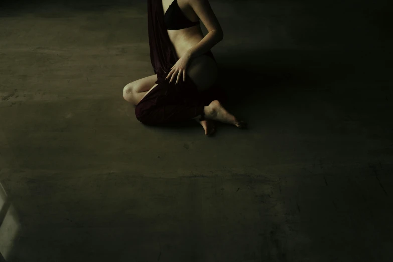 a woman sitting on the ground in a dark room, an album cover, inspired by Katia Chausheva, unsplash, figurative art, belly dancing, on the concrete ground, pregnant belly, ilustration