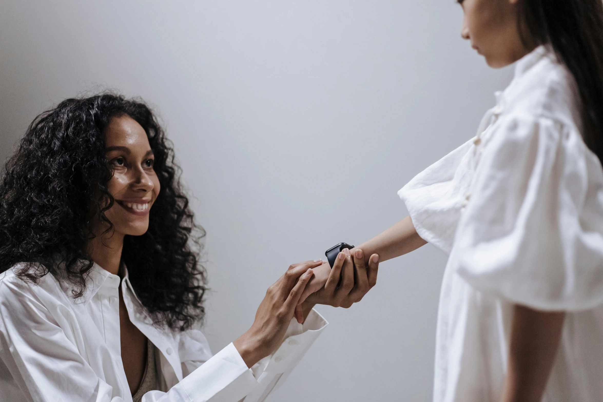 a woman shaking hands with another woman in a white shirt, by Emma Andijewska, pexels contest winner, interactive art, wears a watch, imaan hammam, little kid, skincare