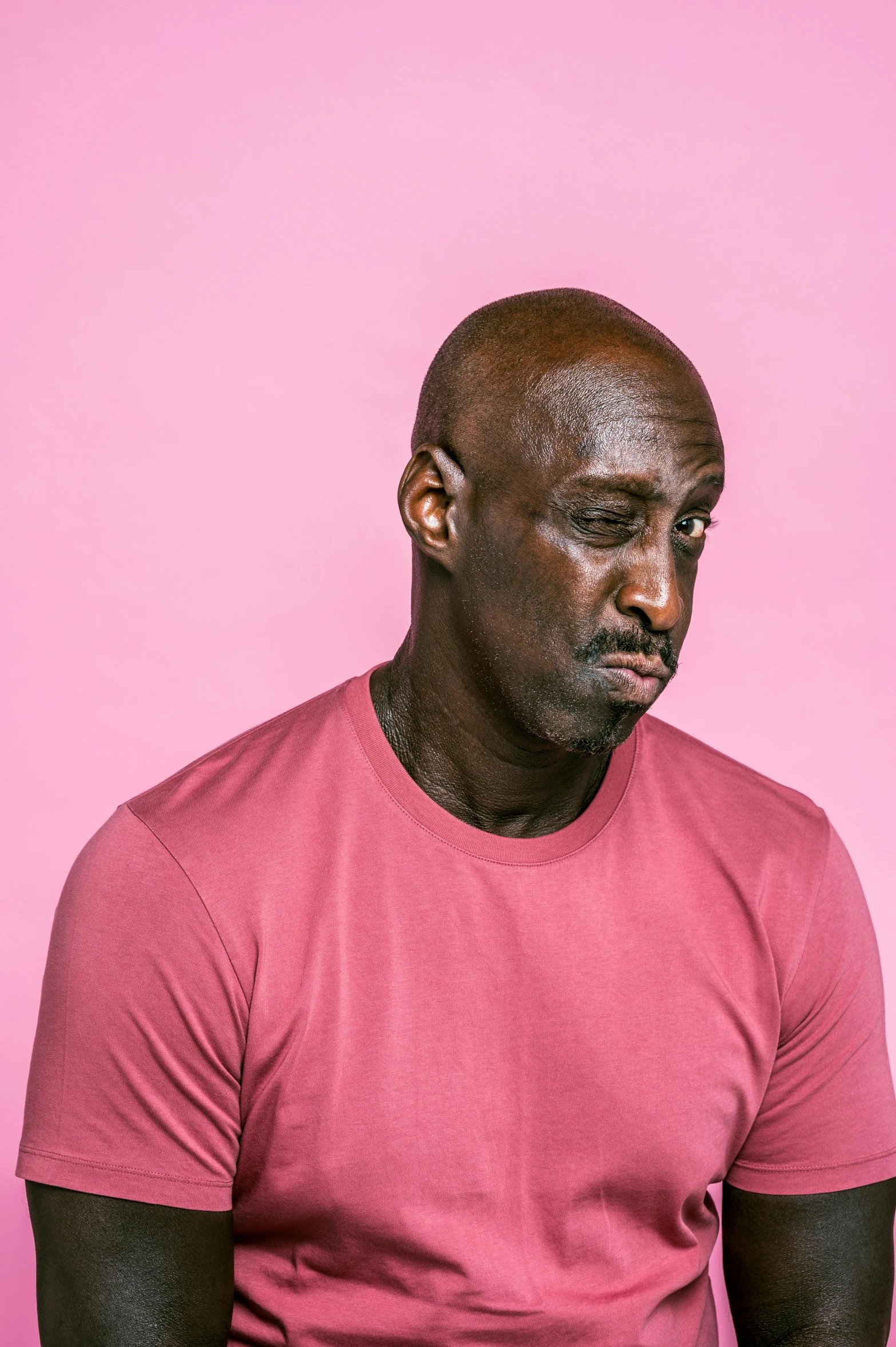 a man sitting in front of a pink wall, an album cover, inspired by George Bain, trending on pexels, lance reddick, on clear background, pouty, shaq