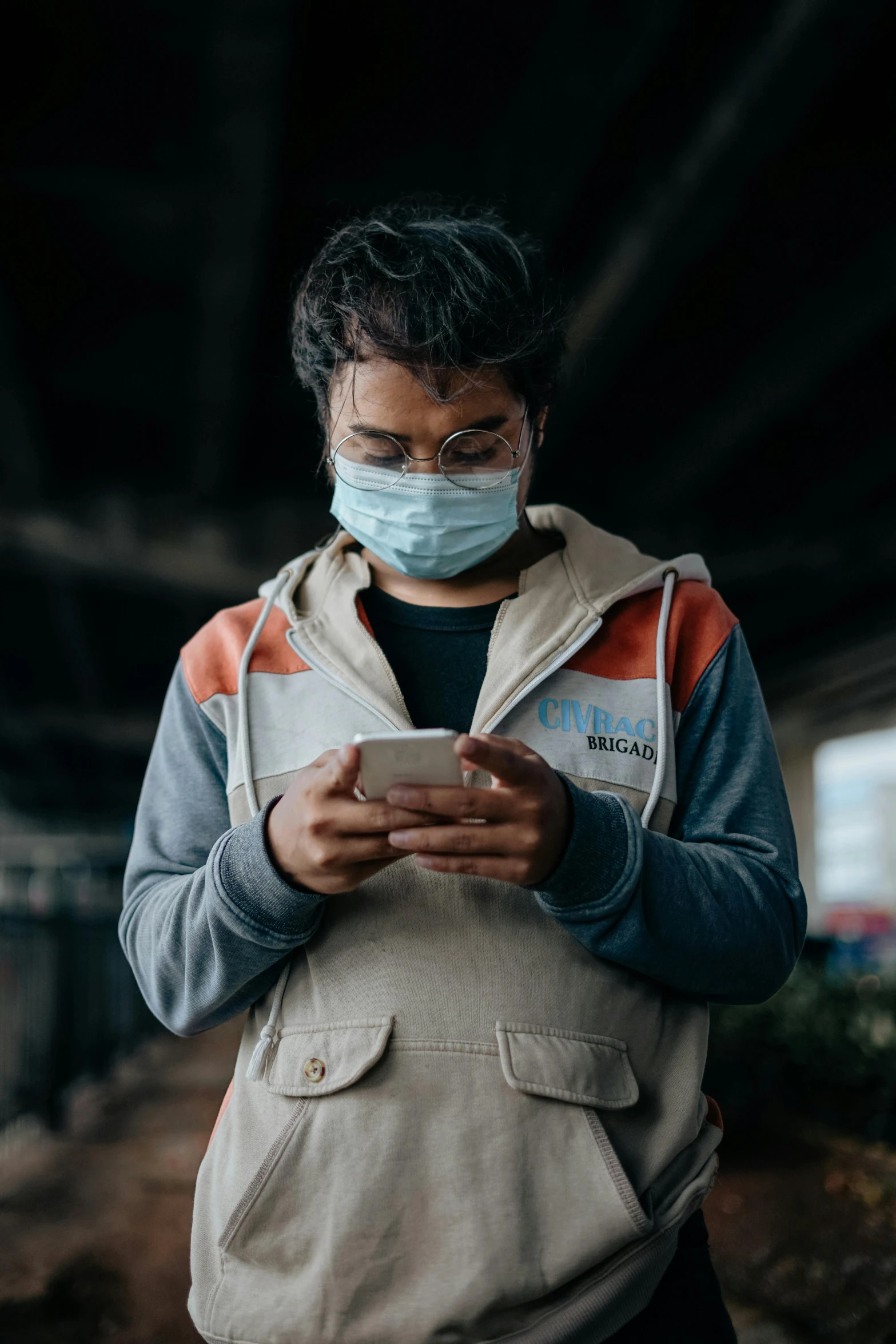 a man wearing a face mask looking at his phone, trending on pexels, nepal, healthcare worker, game ready, grey