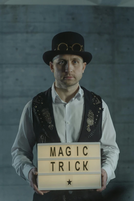 a man holding a sign that says magic trick, by Adam Marczyński, magical realism, wearing steampunk top hat, press shot, hazy, cardistry