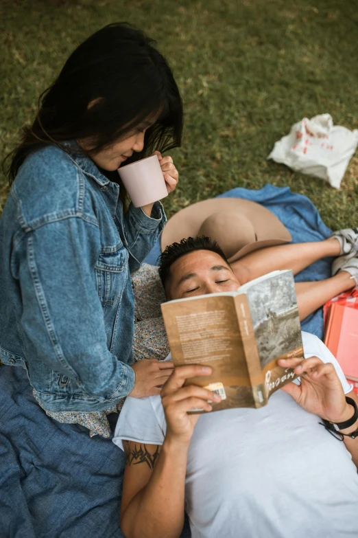 a couple of people that are laying in the grass, holding a book, 2019 trending photo, sydney park, 1 4 9 3