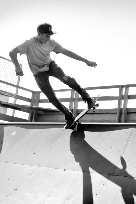 a man riding a skateboard up the side of a ramp, a black and white photo, parapets, denim, uploaded, deck