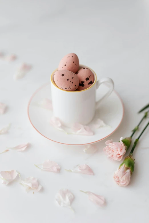 a cup filled with pink eggs sitting on top of a saucer, celebration of coffee products, edible flowers, white with chocolate brown spots, freckles on chicks