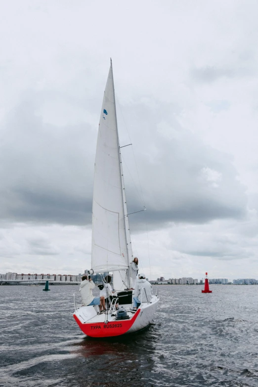 a red and white sailboat on a body of water, while it's raining