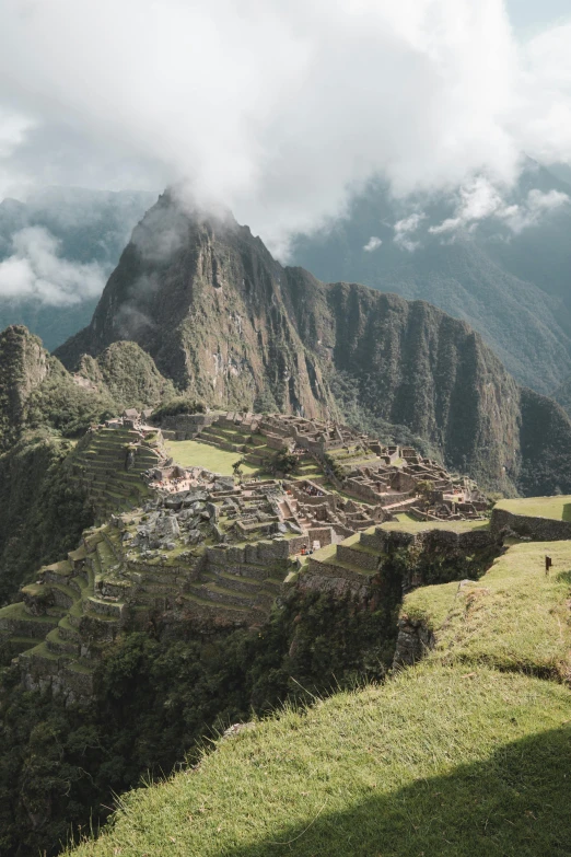 a man standing on top of a lush green hillside, trending on unsplash, machu picchu, 4 k cinematic panoramic view, tiny people walking below, ruins