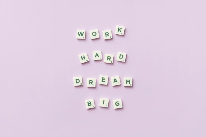 letters spelling work hard dream big on a pink background, pastel purple background, no bricks, hrd, self confidence