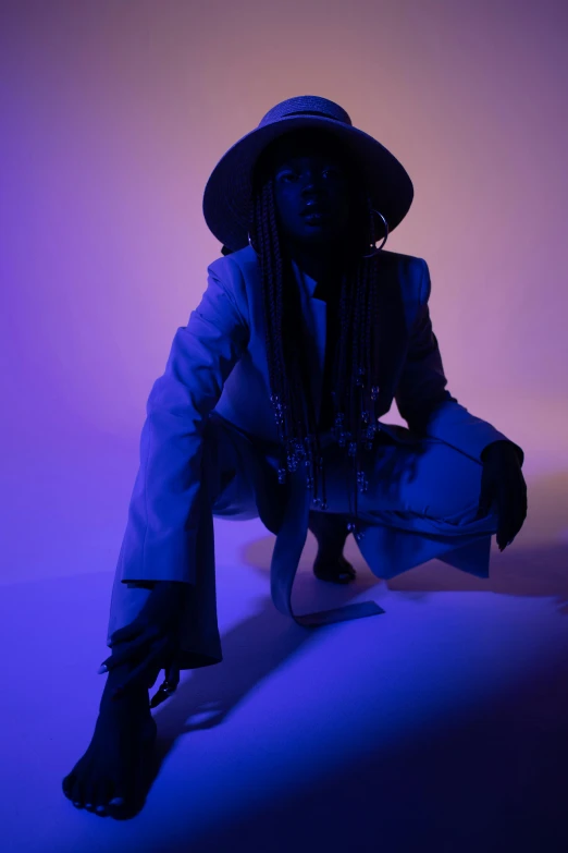 a woman sitting on a stool wearing a hat, an album cover, by David Eugene Henry, trending on pexels, afrofuturism, blue and purle lighting, androgynous person, pose 4 of 1 6, lowkey lighting