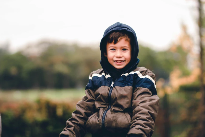 a young boy riding on the back of a bike, pexels, visual art, model wears a puffer jacket, happily smiling at the camera, at the park, wearing farm clothes