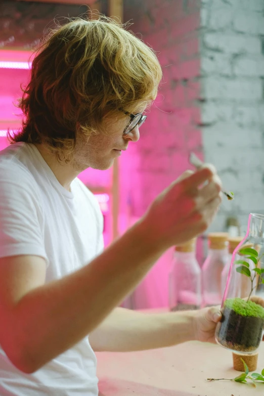 a man sitting at a table with a plant in a vase, experimenting in her science lab, ed sheeran, profile image, plating